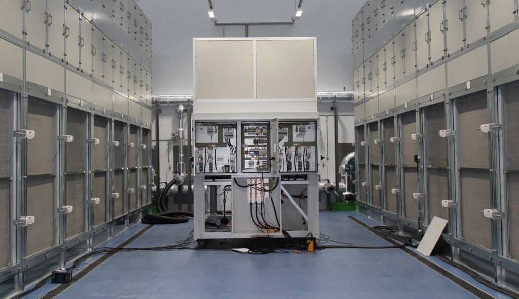 A large industrial room with metal cabinets and a central machine with cables and components.